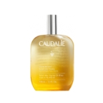 Un flacon transparent d'Huile Sèche Nourrissante Caudalie au Parfum Coco, Fleur d'Oranger et Jasmin, 100 ml, muni d'un bouchon argenté, contenant des huiles nourrissantes telles que l'argan, la figue et le karité pour une peau douce, et dégageant un parfum de noix de coco, de fleur d'oranger et de jasmin. Dakar