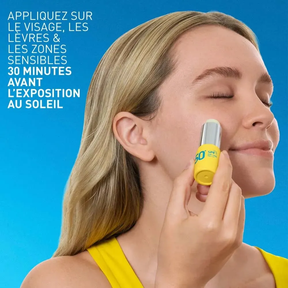 Une femme applique le stick solaire invisible CeraVe SPF 50+ pour le visage, les lèvres et les zones sensibles (peaux sensibles) 8 g sur sa joue, devant un fond bleu. La notice en français recommande de l'appliquer sur le visage, les lèvres et les zones sensibles 30 minutes avant l'exposition au soleil. Dakar