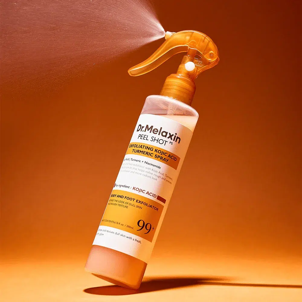 Dr Melaxin Spray Exfoliant à l'Acide Kojique et au Curcuma Peel Shot 200 ml est vaporisé, libérant une fine brume de son embout orange sur un fond orange. Dakar