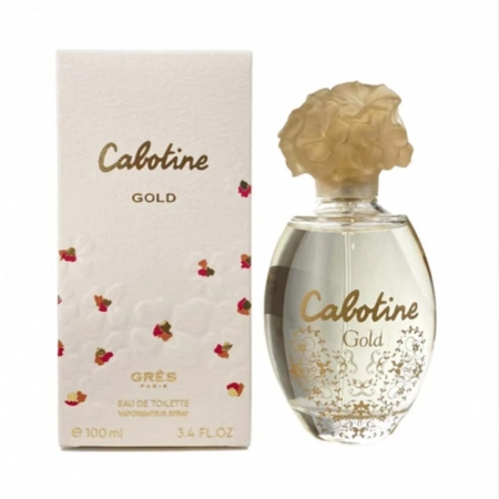 Un flacon de 100 ml d'eau de toilette Cabotine Gold de Grès Paris est posé à côté de son coffret blanc et doré, tous deux ornés de motifs floraux et d'inscriptions dorées. Le flacon est muni d'un bouchon doré en forme de fleur. Dakar