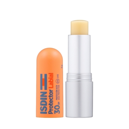 Un baume à lèvres Isdin Protector Labial Stick SPF 30 au beurre de karité et au panthénol (4 g), dont le bouchon orange a été retiré, laissant apparaître le baume jaune pâle à l'intérieur d'un tube argenté aux lignes épurées. Dakar