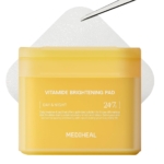 Un récipient jaune de Mediheal Disques de Soin Masque Éclaircissants et Purifiants 100 Pièces est représenté, avec un tampon texturé partiellement visible derrière lui et une pince à épiler tenant le tampon dans le coin supérieur droit. Dakar