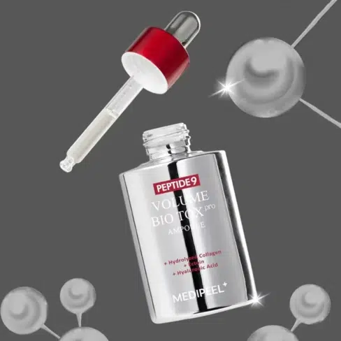 Un flacon argenté de Medipeel Sérum en Ampoule Éclat Anti Age Peptide 9 Volume Biotox Ampoule Pro 100 ml avec un compte-gouttes à bouchon rouge se détache sur un fond gris avec des graphiques de molécules sphériques. Dakar