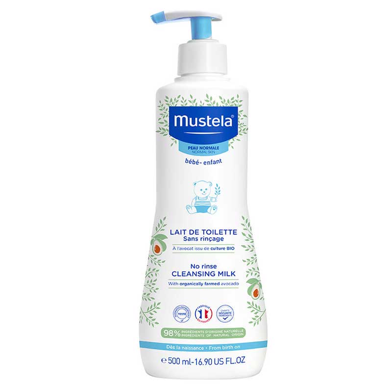 Une bouteille blanche de 500 ml de « Lait de Toilette Sans Rinçage à l'Avocat Bio » de Mustela, dotée d'un flacon-pompe bleu, d'une illustration représentant un bébé et de motifs de feuilles vertes. L'étiquette précise que ce produit est destiné aux bébés et qu'il est élaboré à partir d'avocat issu de l'agriculture biologique. Dakar
