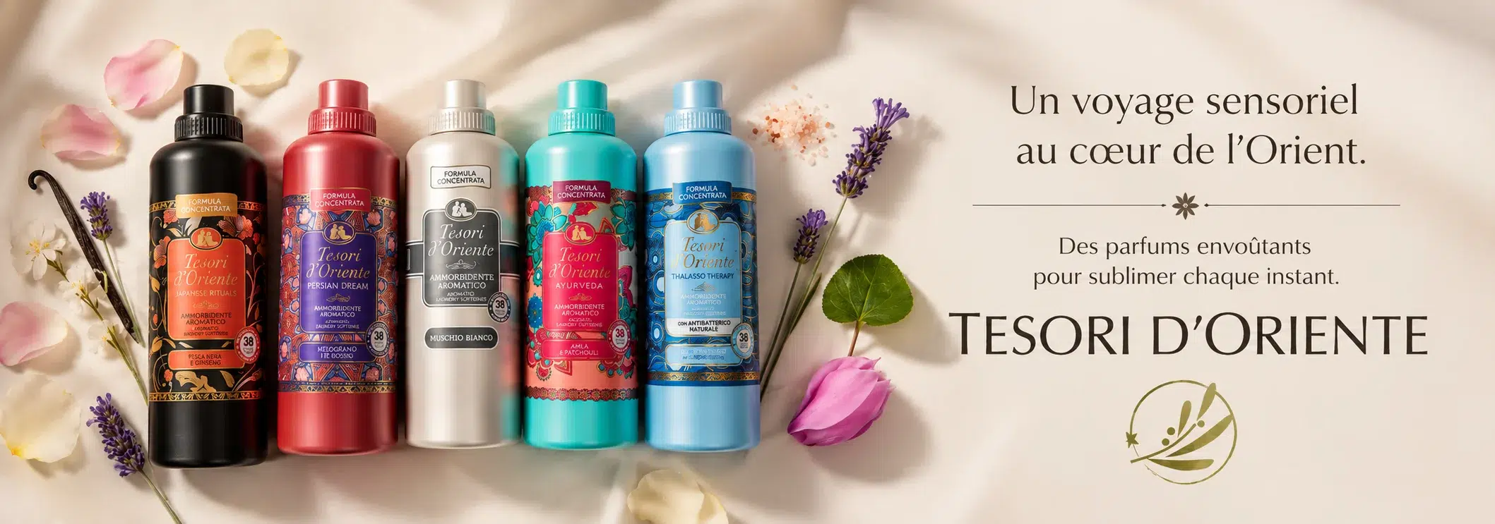 TESORI-dorient-parfums-senegal-dakar-universcosmetix Cinq flacons colorés de produits pour le bain « Tesori d’Oriente » de la marque Univers Cosmetix sont disposés sur un tissu soyeux parsemé de pétales de fleurs, de brins de lavande et de l’inscription « Un voyage sensoriel au cœur de l’Orient. TESORI D’ORIENTE. ». Dakar