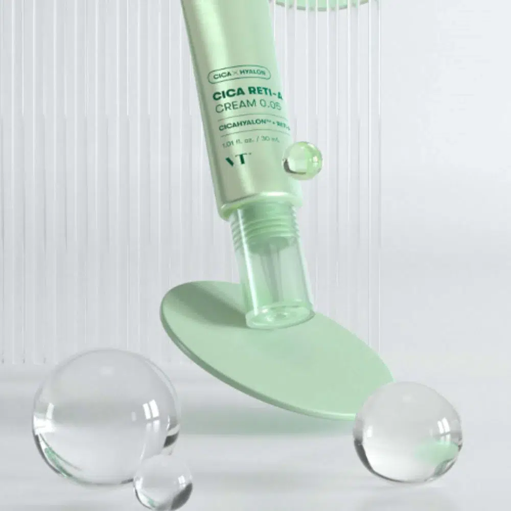 Un tube de Vt Cica Reti A 0.05 Soin Correcteur Anti-Âge au Rétinol et à la Centella Asiatica de 30 ml est représenté debout, sans son bouchon, entouré de sphères en verre transparent et d'un disque vert menthe sur un fond clair et épuré. Dakar