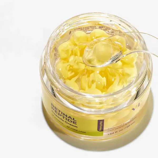 Un flacon transparent portant l'étiquette « Vt Crème en Capsules aux Peptides Rétiniens Anti-Rides et Ridules 50 ml », contenant des capsules de sérum jaunes et une petite cuillère, est posé sur une surface blanche. Dakar