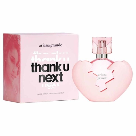 Une boîte rose et un flacon de parfum en forme de cœur portant l'inscription « ariana grande thank u next ». La boîte comporte le nom d'Ariana Grande, le nom du produit et une image floue de son visage. Le flacon est orné d'un motif représentant un cœur brisé. Dakar