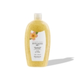 Un flacon en plastique transparent contenant le Gel Douche Exfoliant Revitalisant Fleur de Tiare Peau Lisse et Douce de Byphasse, 750 ml, rempli d'un gel jaune et de microbilles exfoliantes, sur lequel figurent une fleur de plumeria et un texte en français, projetant une ombre sur un fond blanc. Dakar