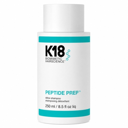 Un flacon blanc de shampoing détoxifiant « Peptide Prep » de la gamme K18 Biomimetic Hairscience, d'une contenance de 250 ml (8,5 fl oz), orné de touches et d'inscriptions de couleur bleu sarcelle, posé à la verticale sur un fond blanc uni. Dakar