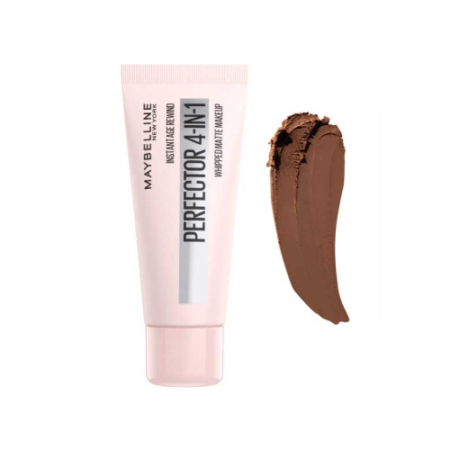 Un tube de maquillage « Instant Age Rewind Perfector 4-en-1 » de Maybelline est présenté à côté d'un échantillon de maquillage crème brun foncé sur fond blanc. Dakar