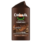 Un flacon de gel douche Ushuaïa de couleur marron portant la mention « Tonifiant Energise », orné d'une illustration représentant du bois de cèdre et d'un texte évoquant l'extrait de cèdre de La Réunion. Dakar